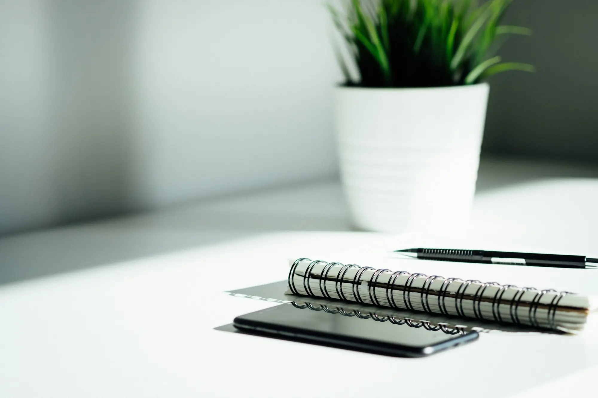 Notebook and pen on a white desk for keeping track of statements