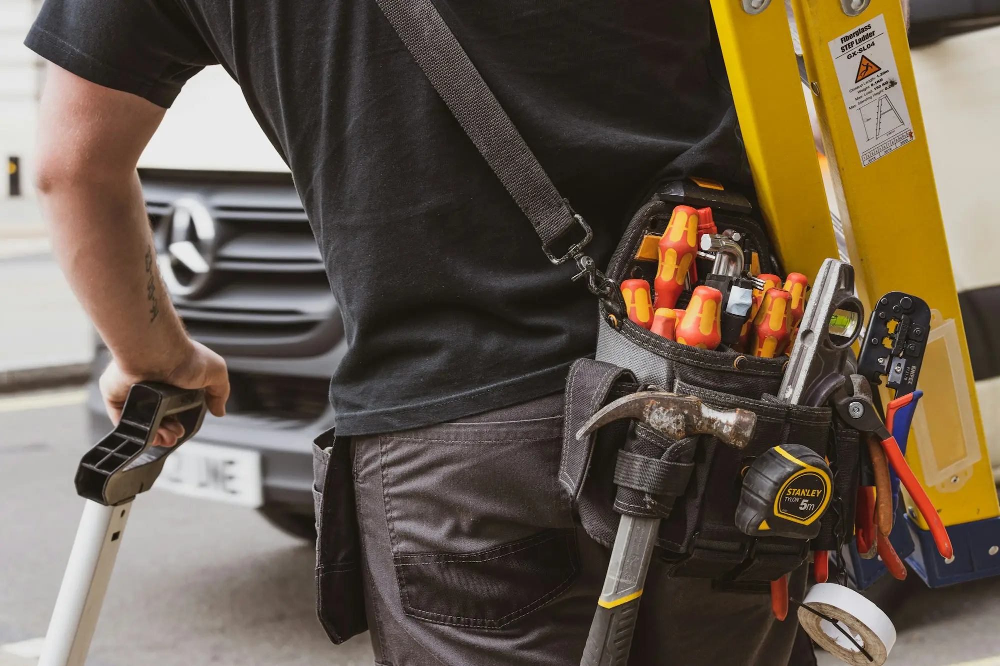 Tradie with a tool belt beside his ute